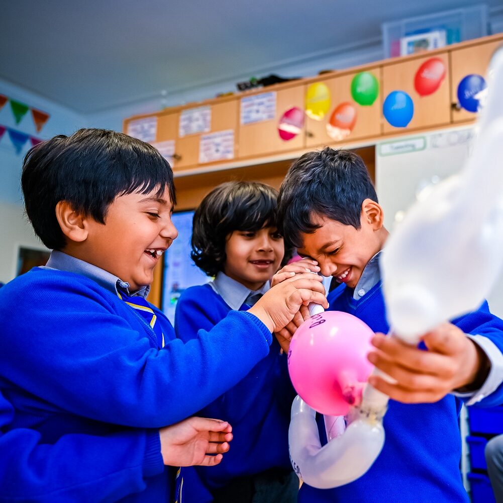 Junior Department pupils do a science experiment with balloons in a classroom.