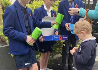 Three Year 8 boys sell poppies to a Nursery pupils.