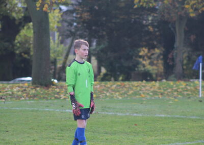 The 1st XI football team goalkeeper stands on a pitch.