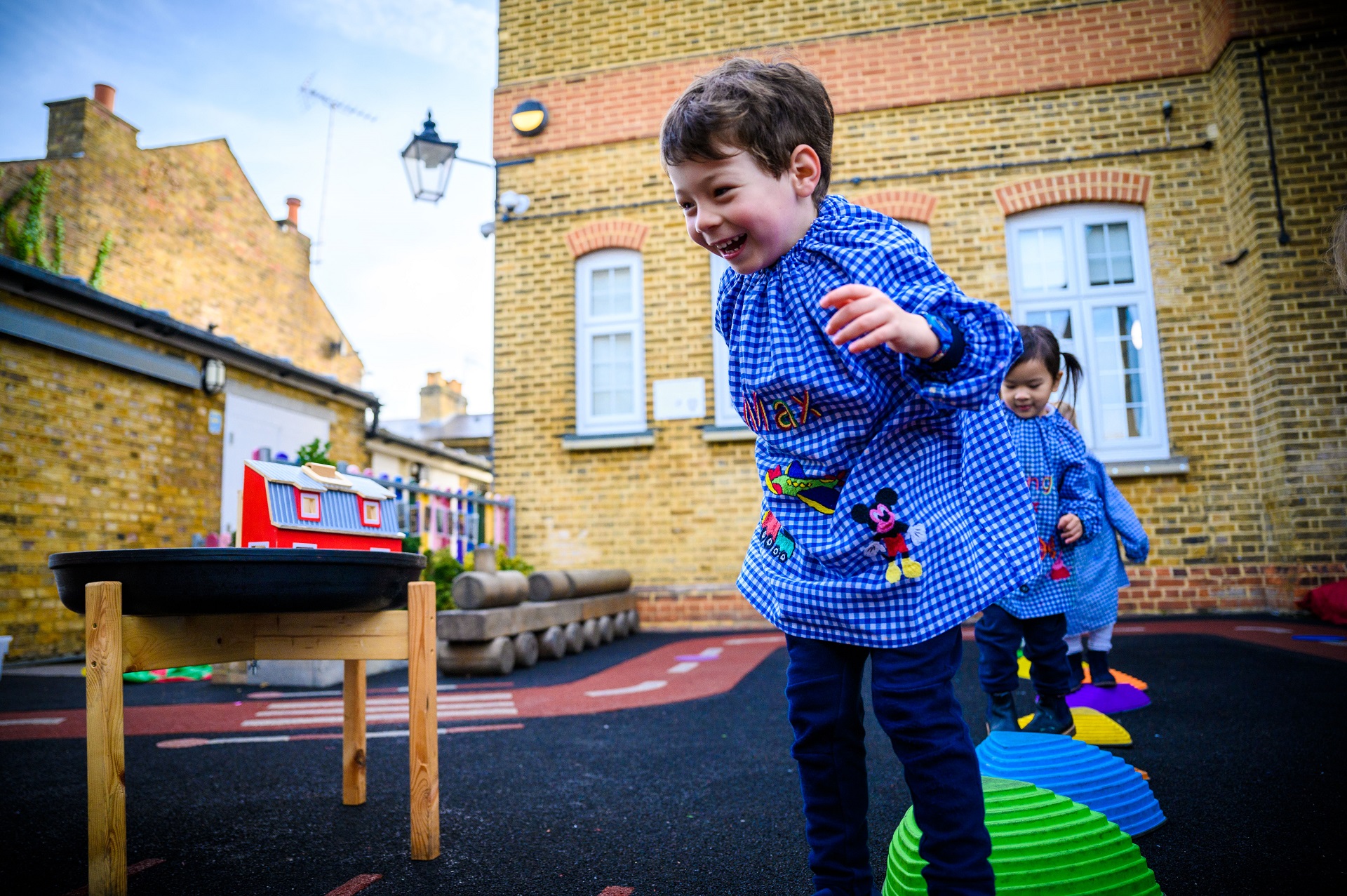 A Nursery pupil runs across the playground, which is full of equipment.