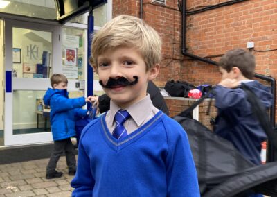 A JD pupil wears a stick on moustache outside school.