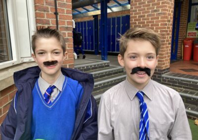 Two SD boys wear stick on moustaches.