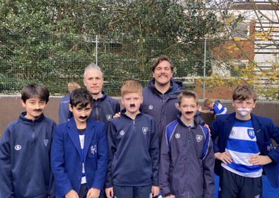 Mr Picknett and Mr Williams stand with SD boys wearing stick on moustaches.