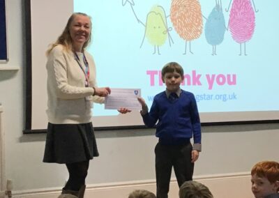 A JD pupil gives a cheque to Shooting Star.