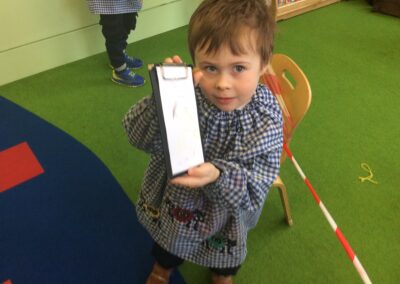A Nursery pupil shows what he's written in a notepad.