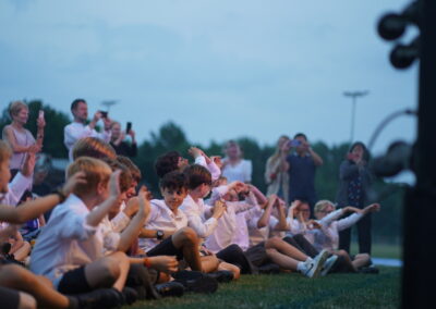 KHS pupils sit on the grass and listen as rock bands perform at the summer concert.