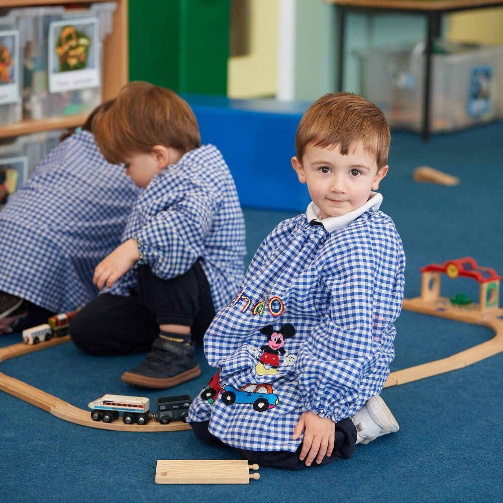 Nursery children play with train tracks.
