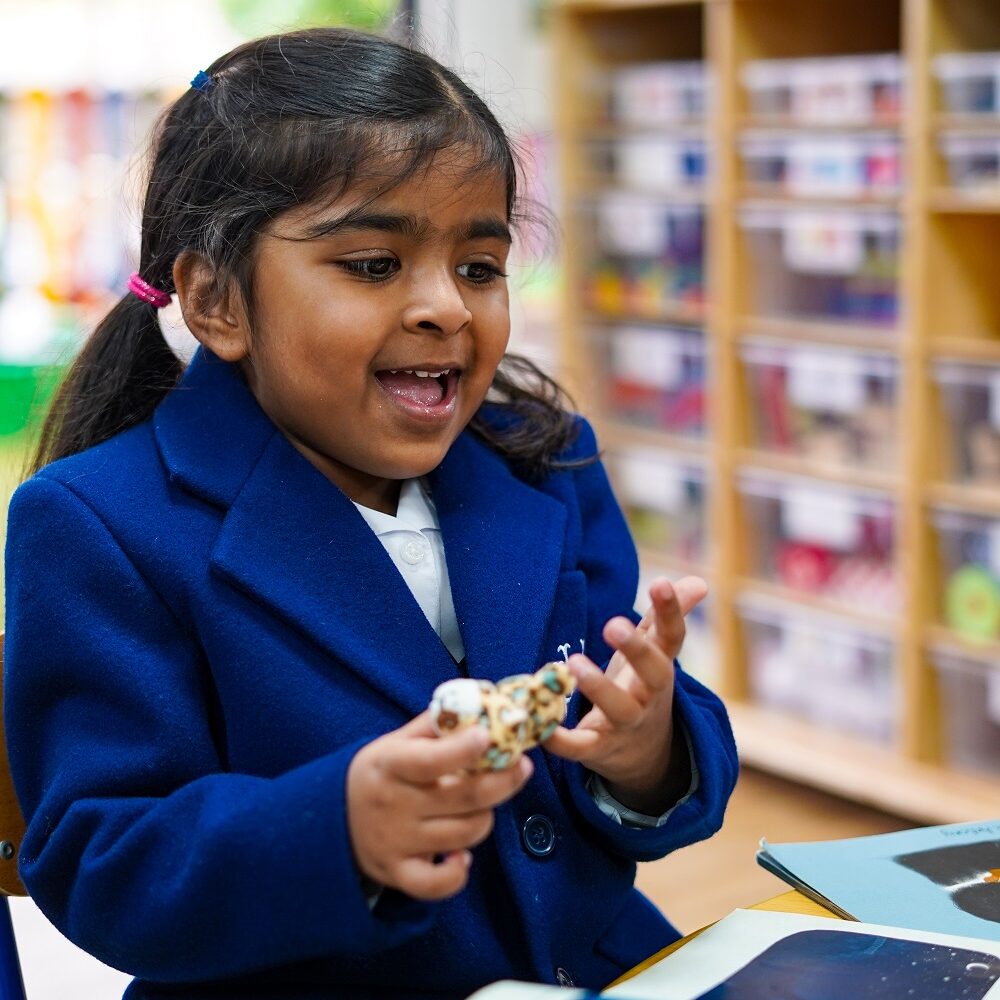 A KHS pupil sits at a table in a Reception classroom playing with a finger puppet.